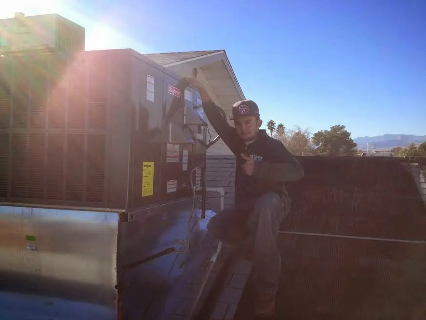 HVAC technician performing Air Duct Cleaning on a rooftop unit in Oakland